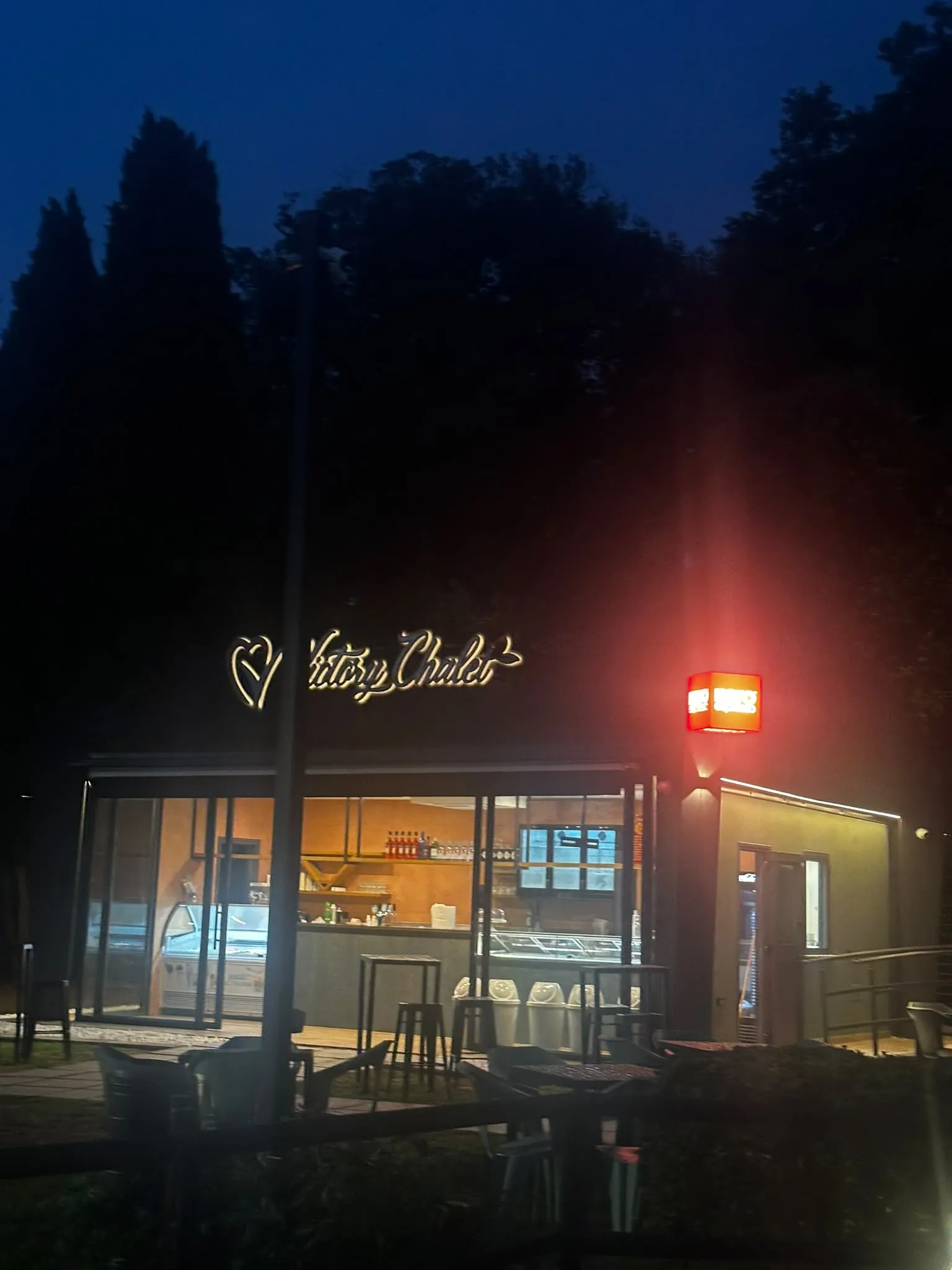 Lo chalet illuminato di sera con l’insegna Victory Chalet