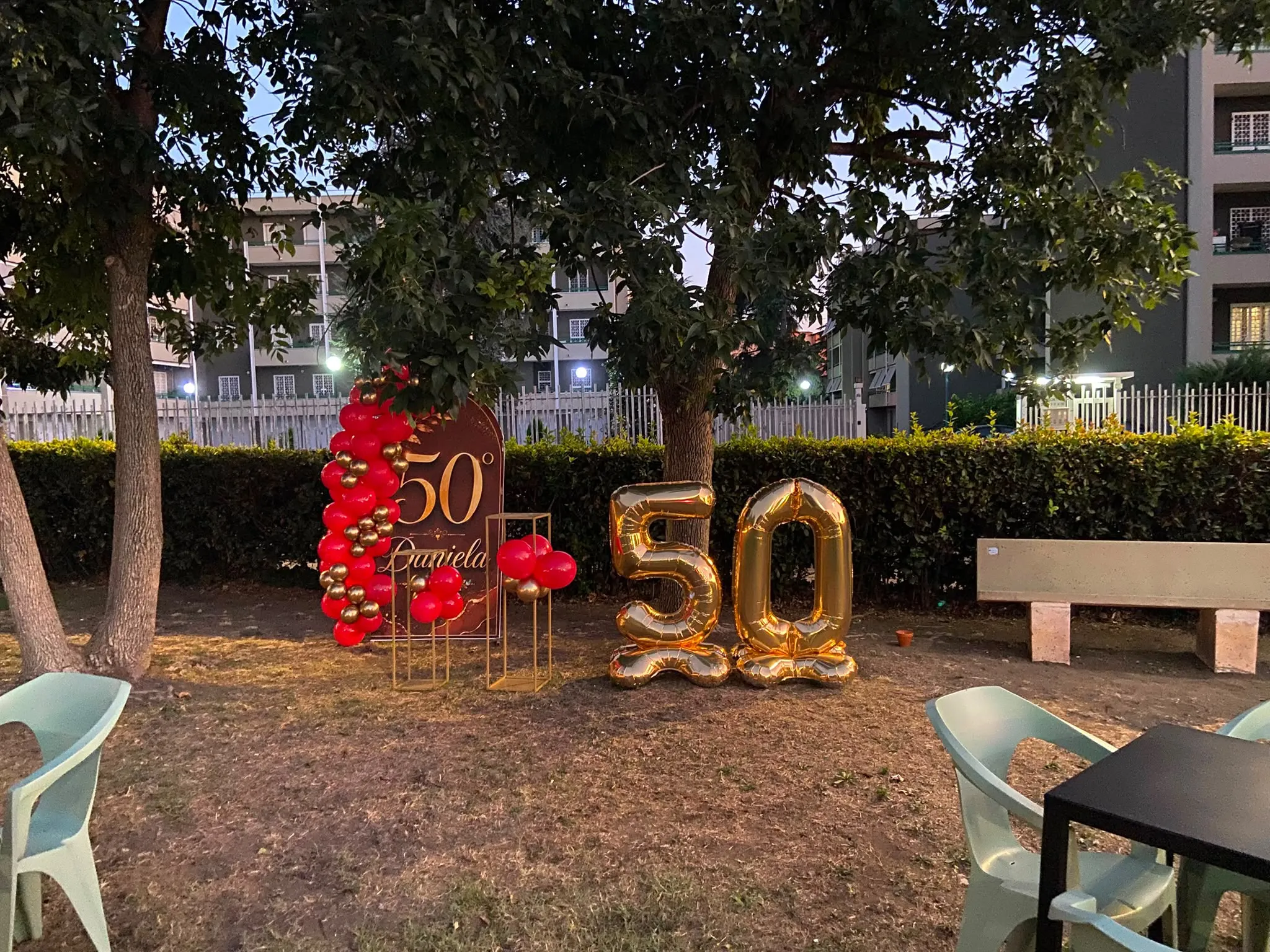 Allestimento con palloncini rossi e oro per una festa di 50 anni nel giardino