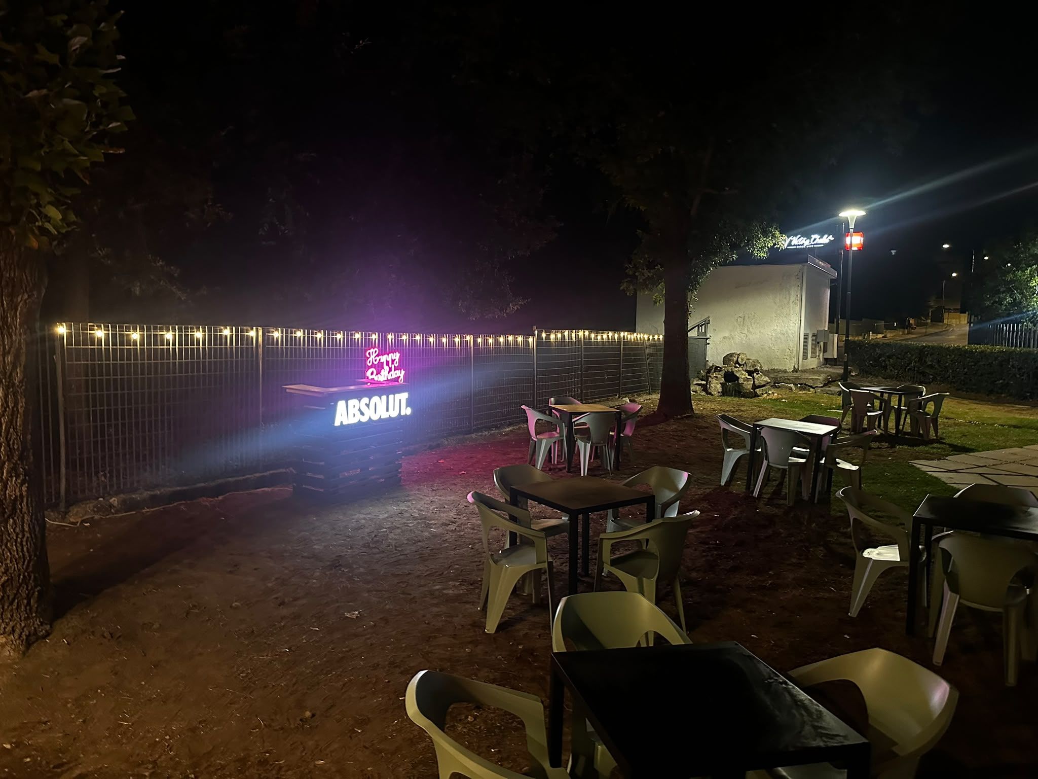 Il giardino del Victory Chalet illuminato di sera, con il bar luminoso e le lucine