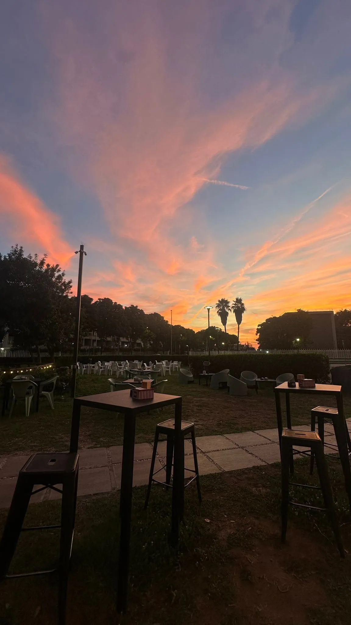 Tavoli alti nel prato sotto un cielo rosa al tramonto